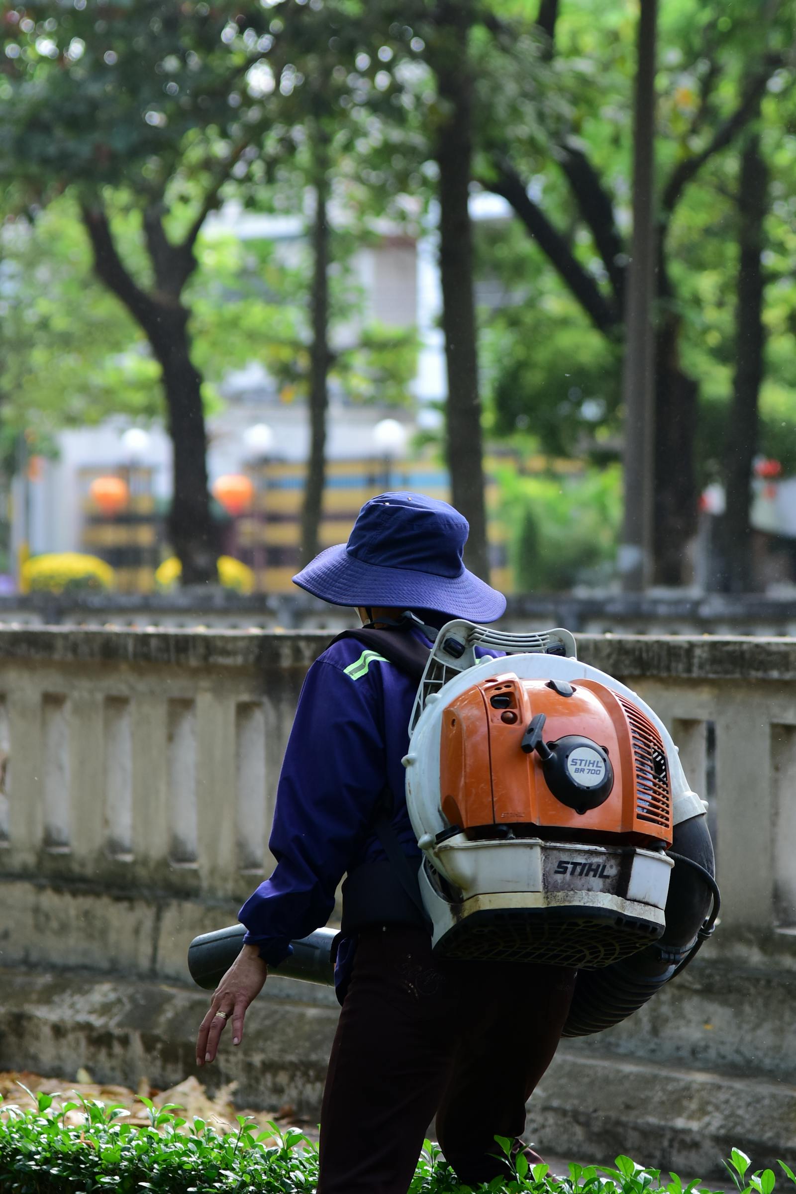 Backpack-blower clearing fronds and leaves into a tidy pile after a monsoon.